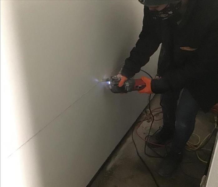 woman cutting out a wall with a tool